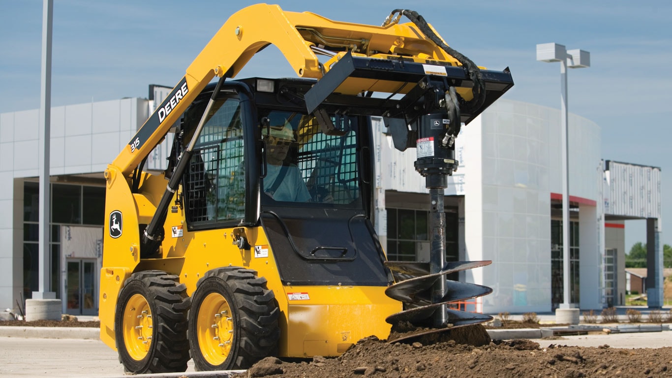 John Deere Skid Steer with Planetary Auger Attachment digging on jobsite.